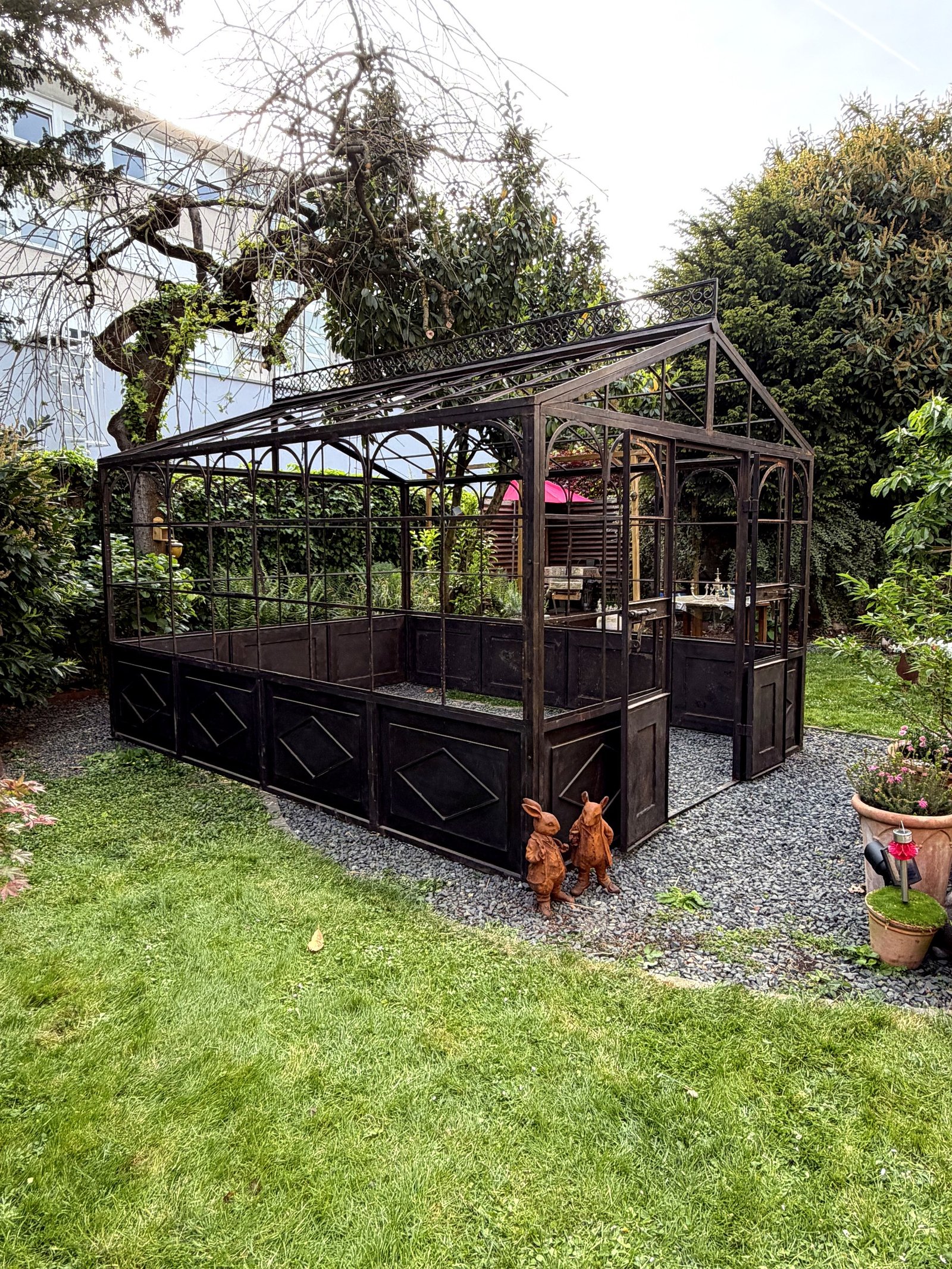 Serre en fer forgé en jardin urbain, vue latérale gauche