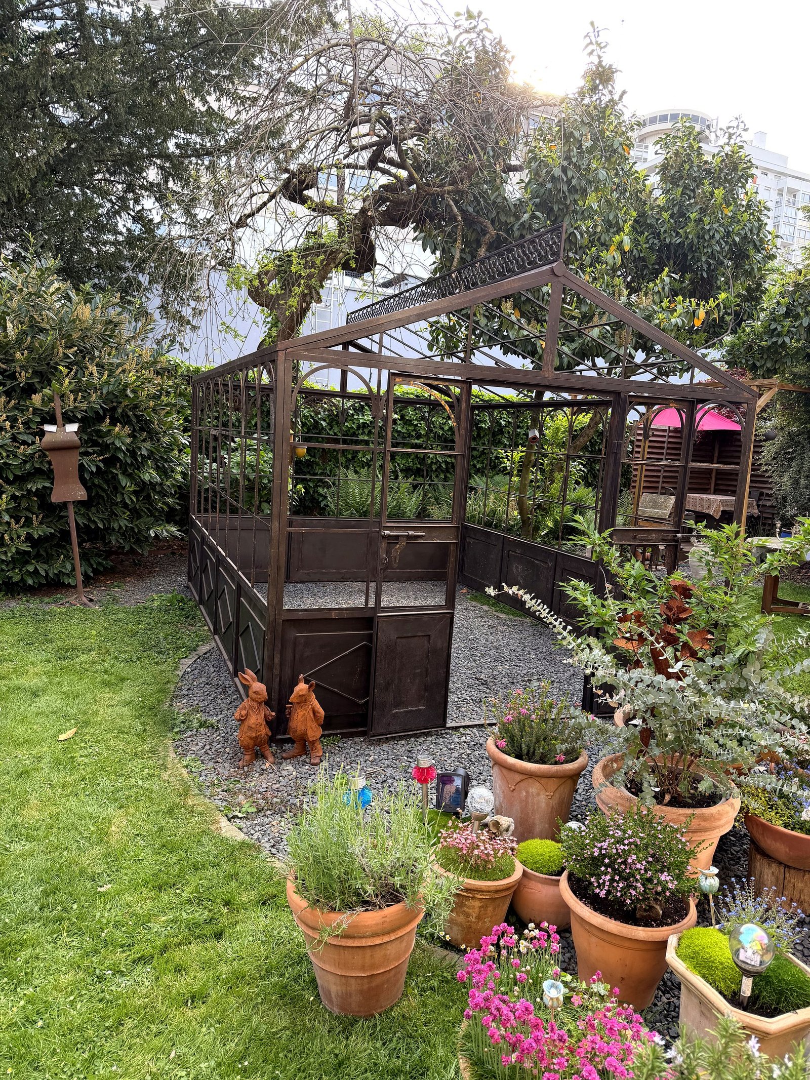 Entrée de serre en fer forgé dans un jardin urbain