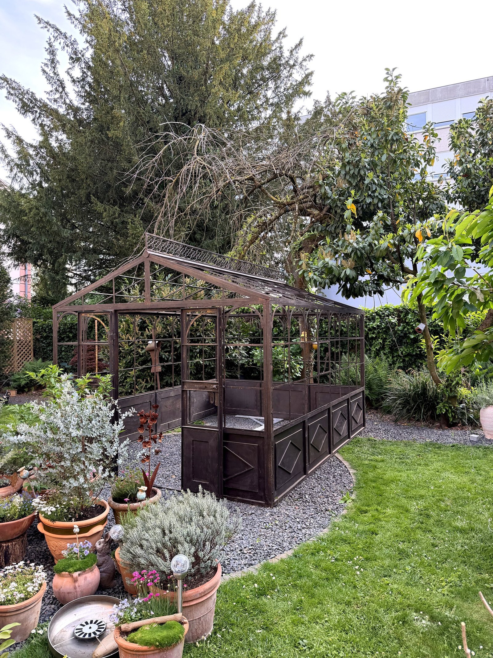 Serre en fer forgé en jardin urbain, vue latérale droite