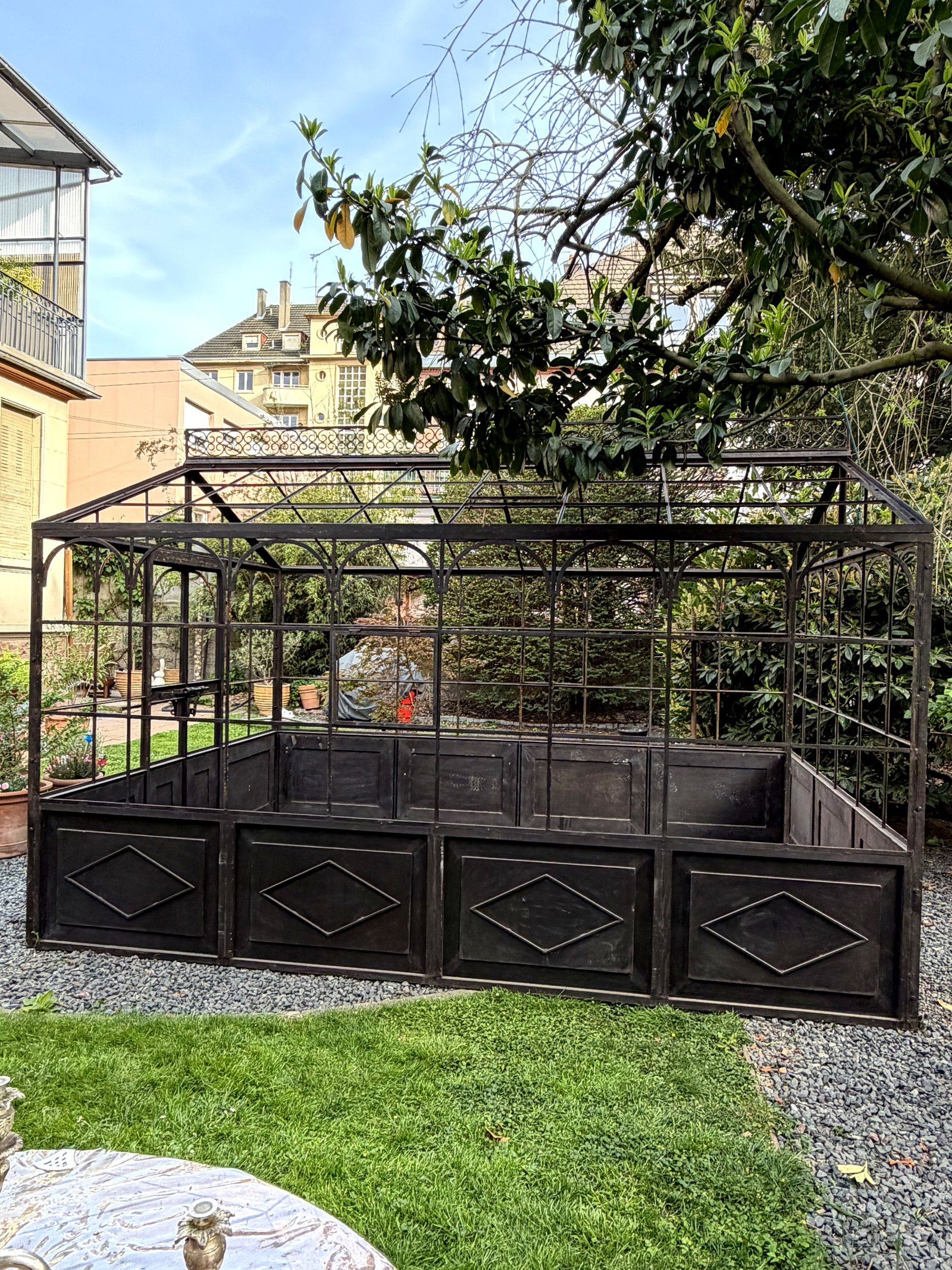 Serre en fer forgé vue de face dans un jardin