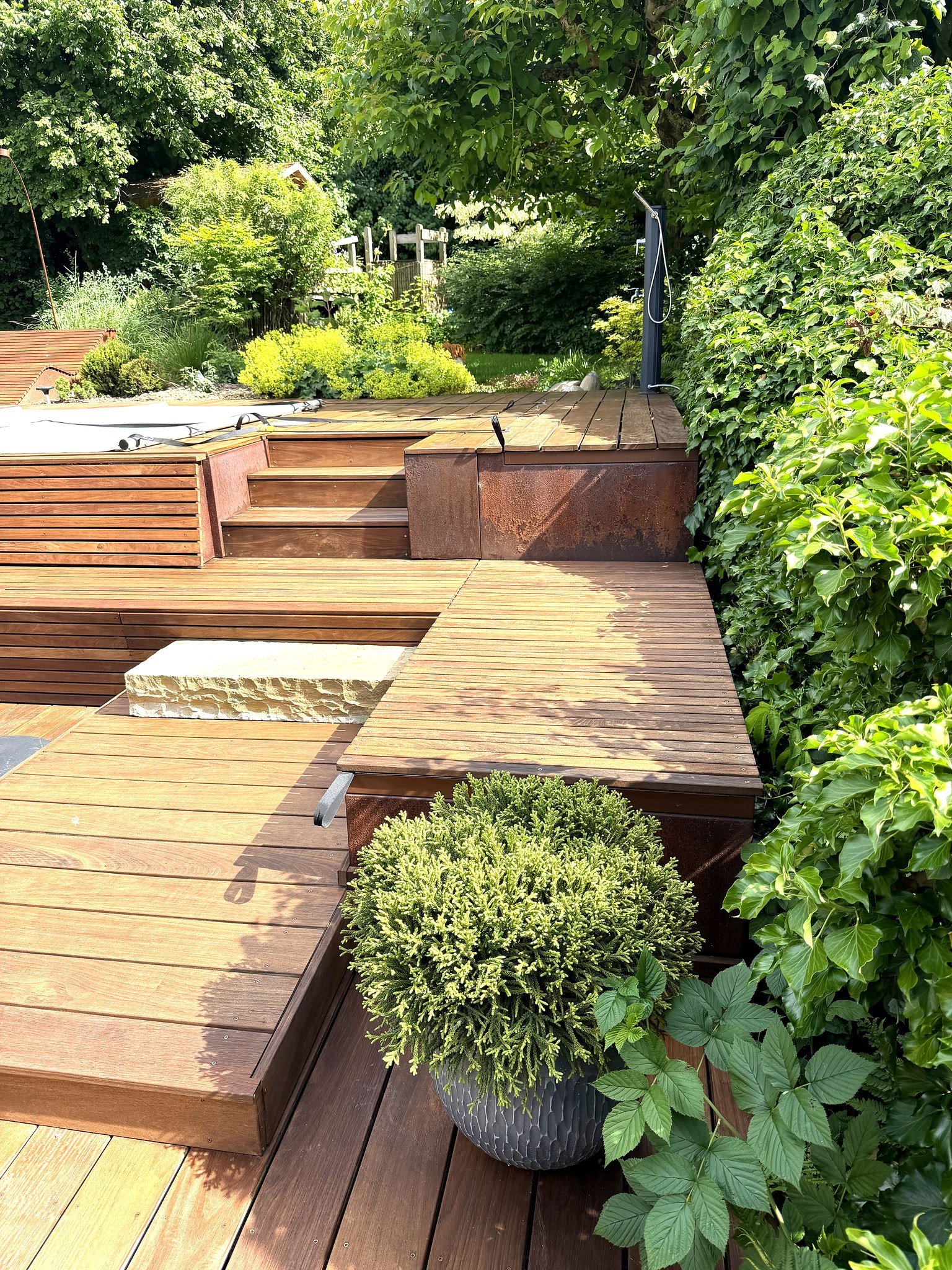 Terrasse en bois multi-niveaux avec marches en acier Corten, spa, buis taille et massif plante — realisation HD Paysage